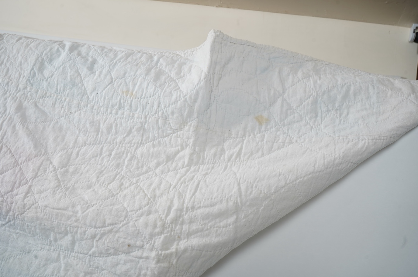A 1900-1910 English, possibly north country hand quilted bedcover. Designed with a large central medallion, hand quilted using mostly pastel patterned and plain cottons and feature red and black cottons as highlights, ba